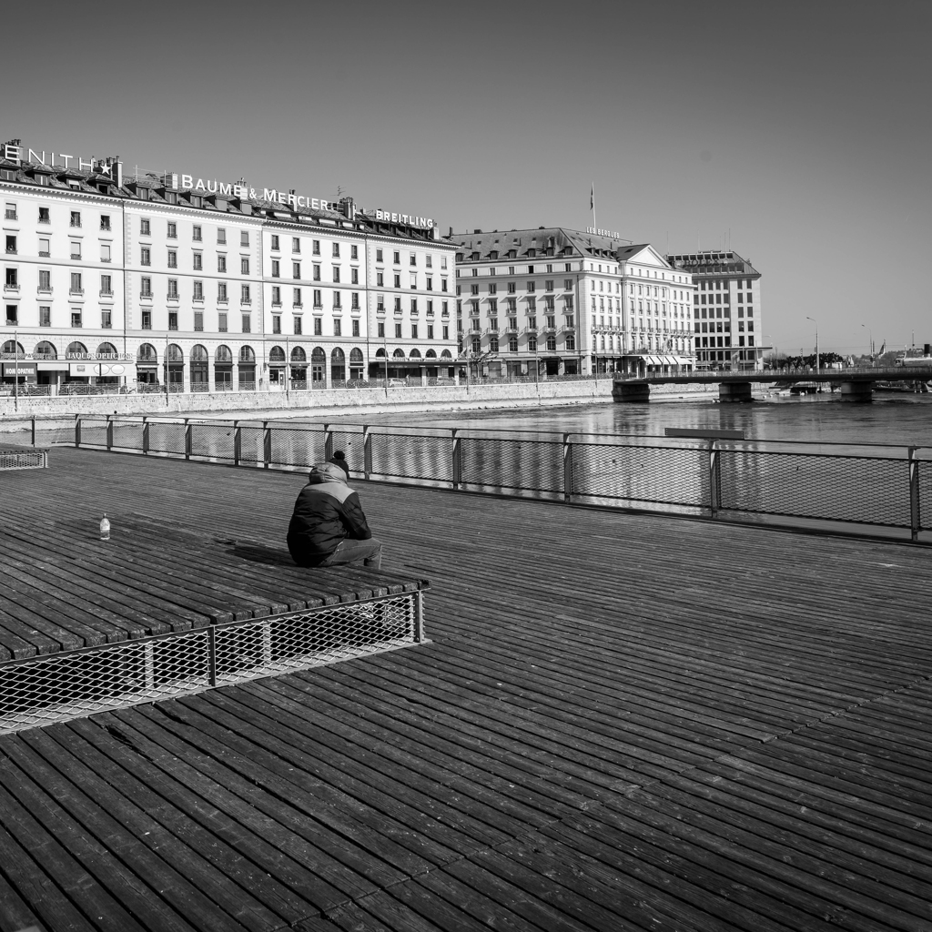 personne assise sur un banc à Genève pendant le confinement 